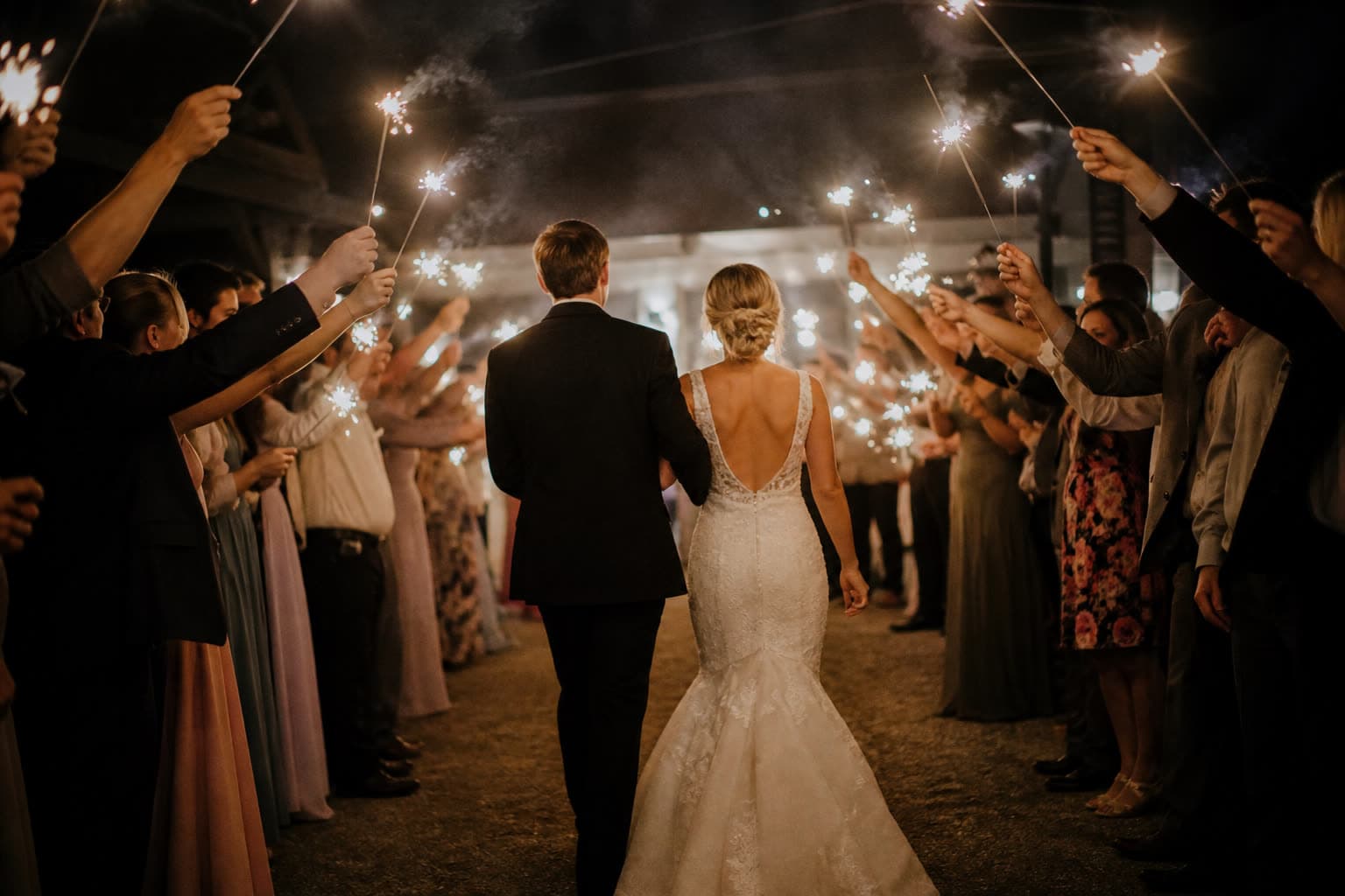 Sparkler send-off as a couple walks through guests at night
